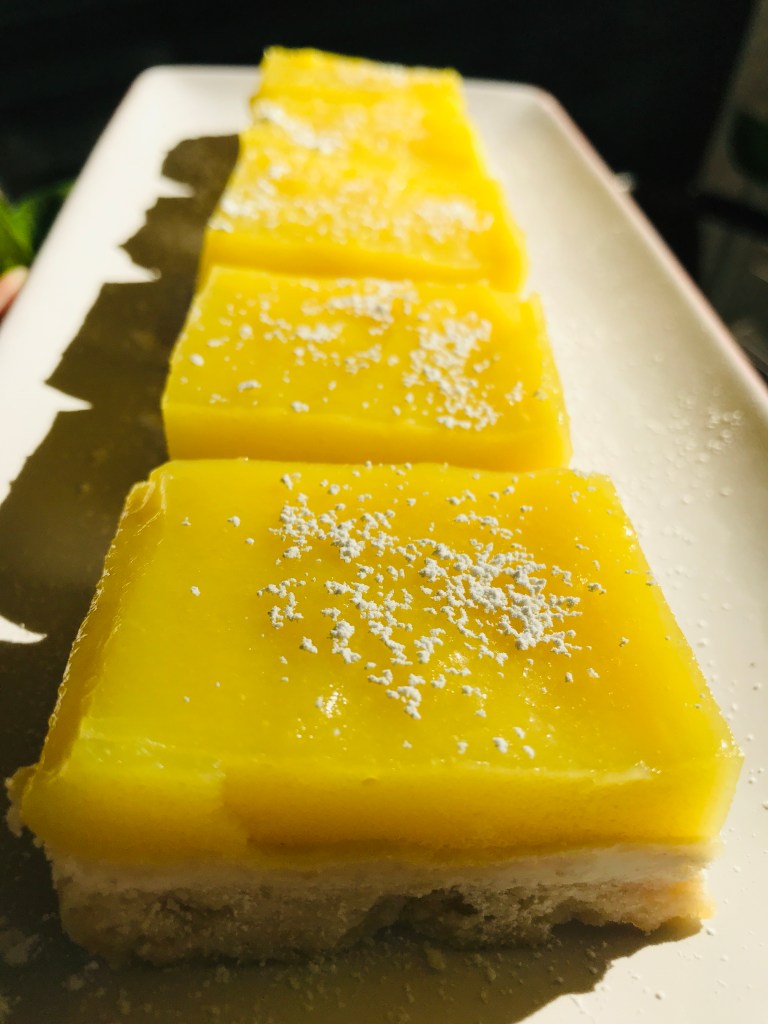 Close-up image of vegan lemon bar square with powdered sugar on a plate